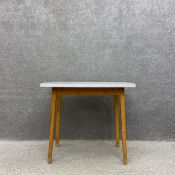 A mid century kitchen table with a grey and white gingham formica top raised on splayed and
