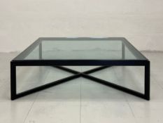 A contemporary coffee table having a square plate glass top set into an ebonised ash frame raised on