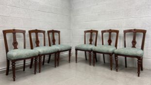 A set of six late 19th century walnut dining chairs with carved backs above upholstered stuffover