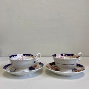 Two 19th century porcelain cups and saucers each hand painted in blues and reds with gilt