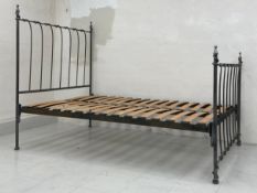 A vintage wrought iron bed frame having simple headboard with ball and spire finials above a