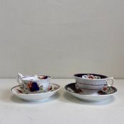 Two 19th century porcelain cups and saucers each hand painted with foliate designs in reds, blues