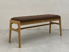 A contemporary Japanese bench by Karimoku having a tweed upholstered seat raised on flat stretchered