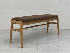 A contemporary Japanese bench by Karimoku having a tweed upholstered seat raised on flat stretchered