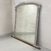A 19th century grey painted overmantle mirror having its original arched plate in a carved and