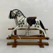 A contemporary hand made fibreglass rocking horse with a dappled finish on a teak stand with a