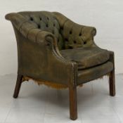 A Georgian style green leather club armchair having a scrolled button back and arms with a cushioned