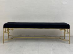 A contemporary bench having a black velvet upholstered stuffover seat raised on brass openwork