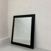 A large C.1900 ebonised and giltwood wall mirror having a rectangular plate in a simple moulded