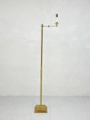 A mid-century brass floor standing reading lamp having an articulated swing arm raised on a narrow