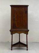 A Georgian oak corner cabinet on stand having a dentil moulded cornice over a single cabinet door
