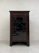 A 19th century mahogany floor standing corner cabinet having a moulded cornice over a carved