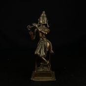 A 19th century or earlier bronze figural statue depicting Krishna playing the flute on a square