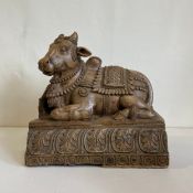 A large 19th century Indian hardwood figural carving depicting a recumbent Nandi; the sacred bull