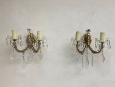 A pair of vintage wall sconces with two curved branches draped with cut glass drops terminating in