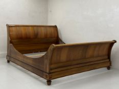 A 20th century walnut sleigh bed frame having a scrolled head and footboard with shaped sides raised