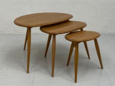 A nest of three mid-century style beech and elm Ercol tables each having a kidney shaped top