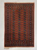 A 20th century hand knotted Tekke Bokhara rug having three rows of fourteen guls over an iron red