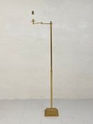 A 20th century brass floor standing reading lamp having an articulated swing arm raised on a