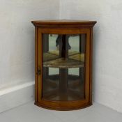 A 19th century walnut bow-front corner display cabinet having a single glazed door opening on to a
