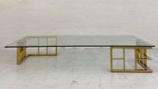 A large contemporary coffee table having a rectangular glass top raised on two opposing polished
