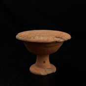 An Indian possibly Gupta period terracotta stamp having a turned handle and bell shaped body with an