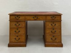 A C.1900 pitch pine twin pedestal desk having a rectangular tooled and gilt red leather top with a