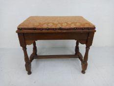 A C.1900 mahogany piano stool having a hinged needlework upholstered top opening to reveal a shallow