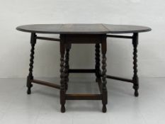 A 20th century oak drop-leaf table having an oval thumb-moulded top raised on a substructure of