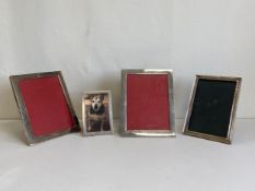 A collection of four white metal picture frames to include a pair with an engraved family crest. L.
