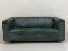 A vintage two seater distressed green leather sofa having a square back and arms over a cushioned