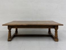 An early 20th century Jacobean style oak low table having a four plank top with a thumb moulded edge