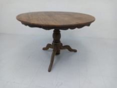 A late 19th century French pine dining table having a circular top with a shaped apron raised on a