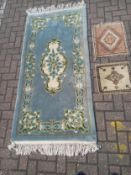 Three rugs to include one with a central medallion over a pale blue ground surrounded by a scrolling