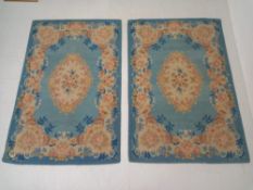 A pair of vintage rugs each having a central flowerhead lozenge medallion in pale pinks over a