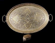 An Indian white metal Kutch silver twin handled tray with an everted rim and all-over scrolling