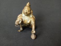 An Indian, possibly 19th century brass figure depicting a Hindu crawling baby Krishna deity. H.8cm
