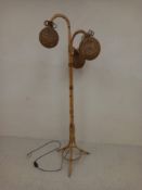 A 1970s retro floor standing bamboo lamp having three bent pendant arms with spherical woven