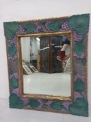 A vintage wall mirror having a rectangular plate in a heavy carved and painted grape and vine