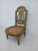 A French Louis XVI style low giltwood side chair having a shaped back with a carved open-work lyre