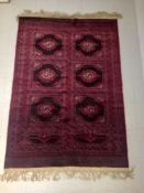 A 20th century Afghan carpet having two rows of three lozenge medallions within dark red borders