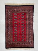 A hand-knotted Bokhara carpet having two rows of eleven guls within multiple concentric geometric