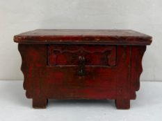 A late 19th century Chinese red lacquered low tea table having a crude rectangular plank top over