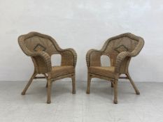 A pair of vintage wicker armchairs each having a shaped serpentine back with curved arms over a d-