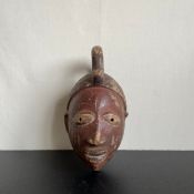 A West African Yoruba Gelede tribal mask from Nigeria having a carved and painted human face with