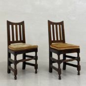A pair of late 17th or early 18th century oak dining chairs each having a shaped top-rail with