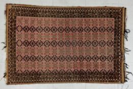 A 19th century Turkaman rug having a flowerhead patterned field in blacks and pale reds over an