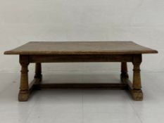 An early 20th century Jacobean style oak low table having a four plank top with a thumb moulded edge