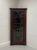 A late 19th century mahogany floor standing corner display cabinet having a dentil moulded cornice