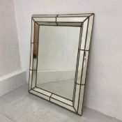 A 20th century wall mirror having a rectangular plate in a panelled mirror and metalwork cushion